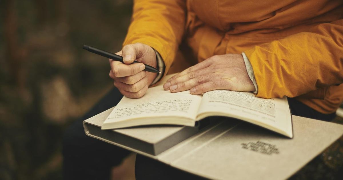 homem escrevendo em um caderno