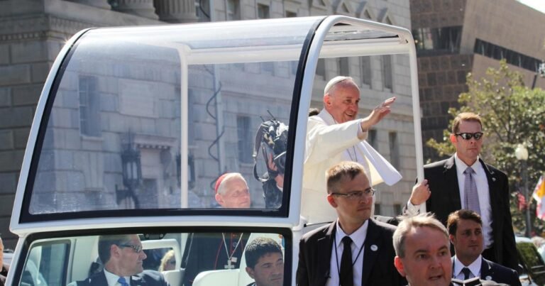 Papa Francisco no papamóvel, cercado por seguranças